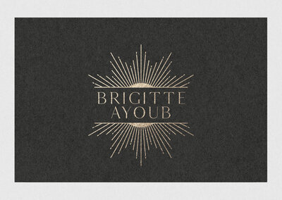 Gold foil logo with text "Brigitte Ayoub" and a sun ray illustration