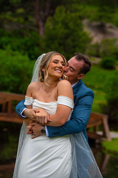A bride and groom dance in a grassy field with yellow flowers with the Boulder Flatirons in the background.