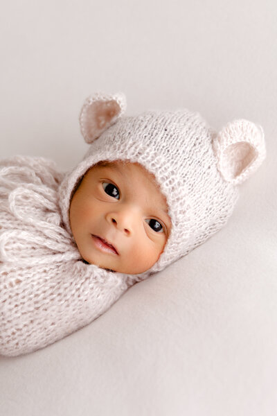 Newborn photo in studio with baby wearing bonnet and smiling
