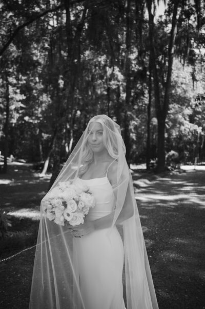 Bride stands with veil covering face