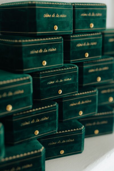 Stack of emerald green velvet jewelry boxes with custom gold calligraphy