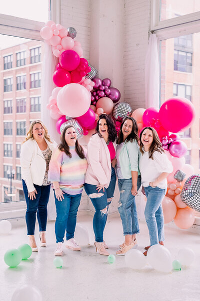 Brand Strategy Chicago Team  photo 5 girls standing in front of a two windows with a balloon bouquet behind them.