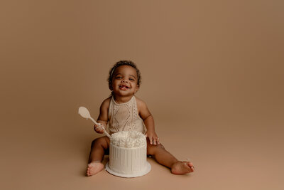 baby eating cake on brown backdrop