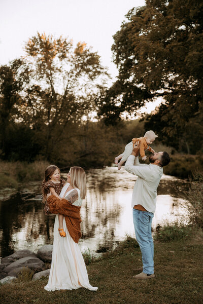 Mom and dad hold each other face to face while their kids fun around them.