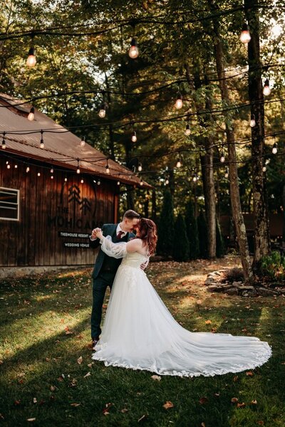 Newlyweds embrace at Mohican Treehouse resort on Fall day,.