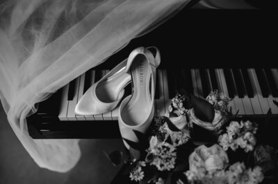 brides shoes, vail and bouquet on a piano