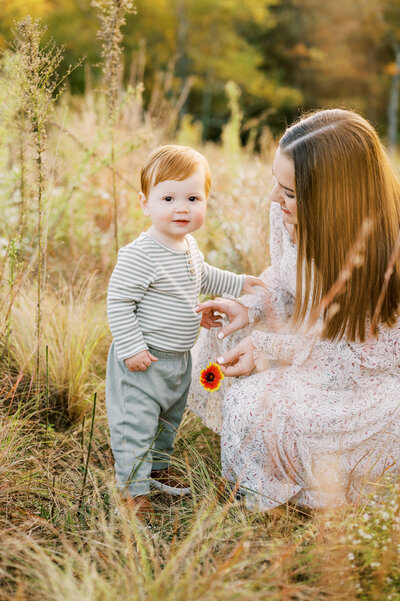 Mom kisses baby girl in a field during fall family session in Raleigh NC