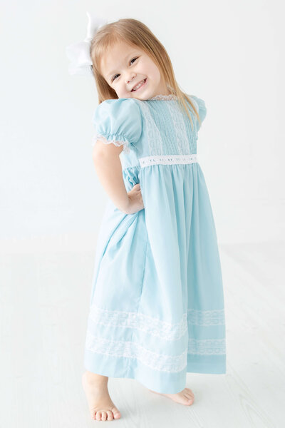 Girl standing smiling at camera in a blue dress