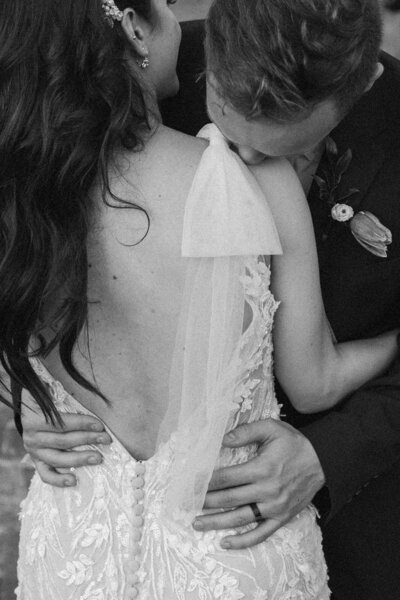 groom kisses shoulder of wife