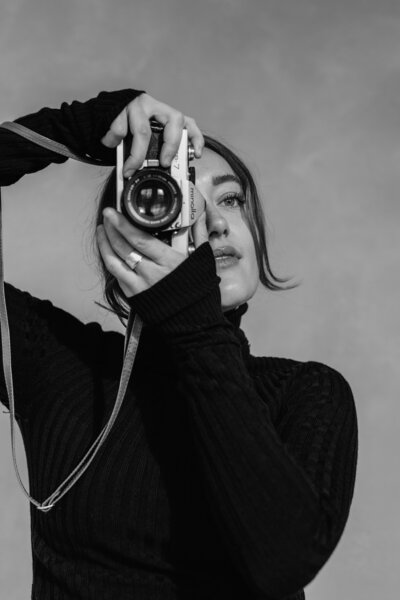Black and white portrait of Laurie Le Bars with a film camera in the studio
