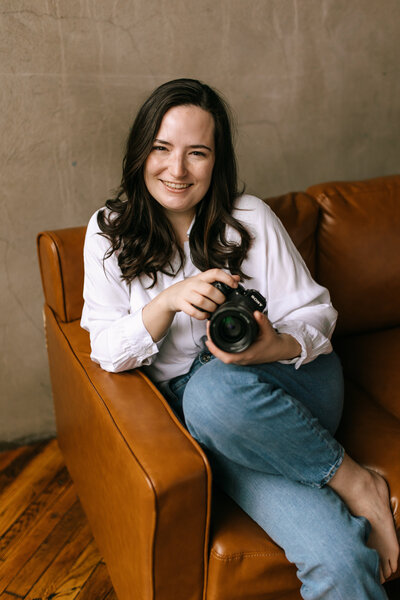 woman with camera sits on couch