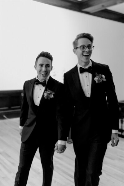 two grooms walking into their reception party