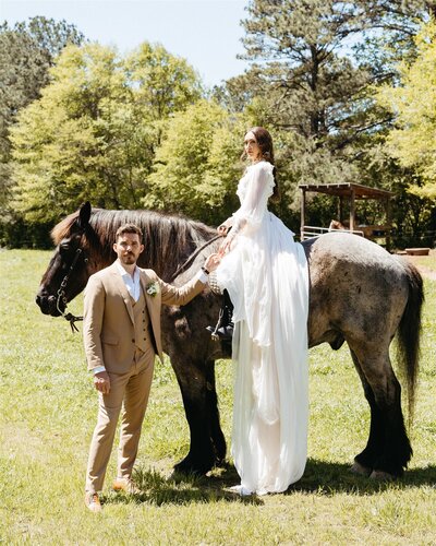 A bride on horseback holding the hand of her groom
