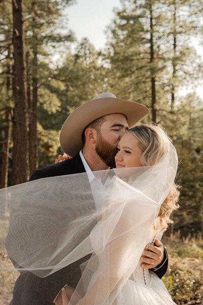 Bride and groom embracing among Strawberry Arizona pines.