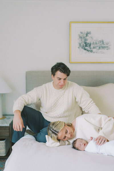 family snuggling on the bed with newborn baby