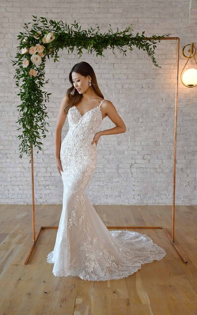VINTAGE-INSPIRED LACE WEDDING DRESS WITH TAPERED TRAIN For a sexy lace look with extraordinary, timeless detail—meet Style 7066 from Stella York. A plunging sweetheart neckline lays beneath a stunning sheer lace feature across the shoulders, creating the softest peek-a-boo effect in the center for a bold touch. The scrolling laces create a slight off-shoulder effect, wrapping around the back to create a stunning back element complete with extravagant, vintage-style scrolling laces on either side of classic fabric-covered buttons. A long, tapered train follows behind to complete the look with a glamorous finish.