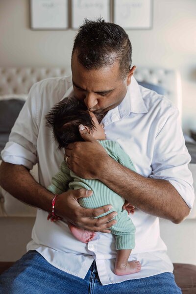 Dad holding baby against chest during newborn session by Taylor Lynn Studios