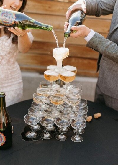 wedding couple pouring champagne over champagne tower