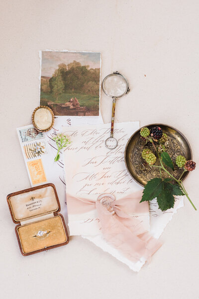 flatlay of items displayed diamond ring invitations vintage postcard envelop golden tray