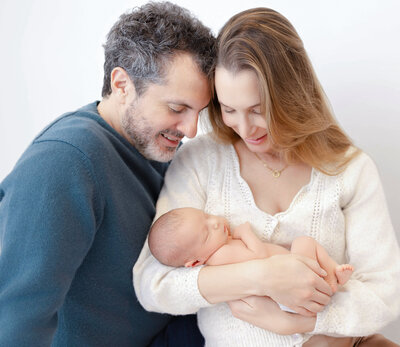 Mother holding two-week old baby in her arms for a photo session at Heather Nicole Photography Studio.