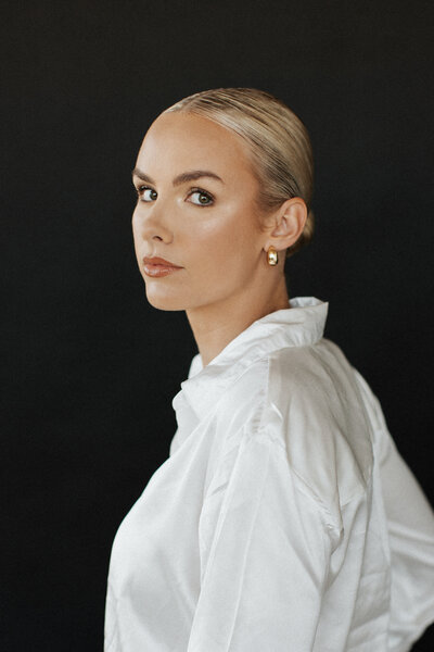 Professional headshot of a salon brand representative against a sleek black backdrop, emphasizing modern elegance and branding.