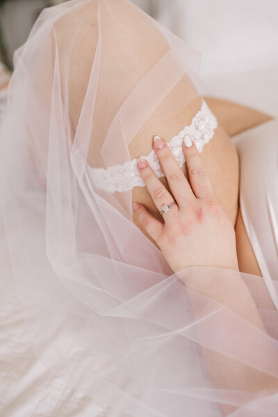 A hand resting on a leg with a garter on it.