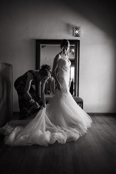 Mother of the bride helping the bride with her dress.