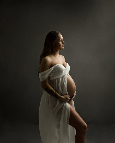 Pregnant woman with a white gown showing her baby bump.