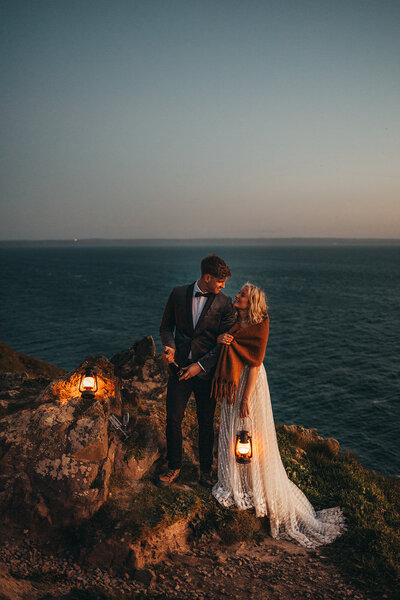 newlywed couple look into each-others eyes by the ocean