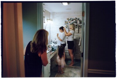 “Bride getting ready with her niece, sister-in-law, and mother-in-law in the bathroom of her fiancé’s home in Fairfax, Virginia — photographed on Kodak Ultramax film.”