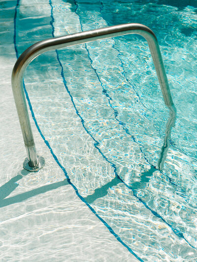 Pool railing and steps with bright blue water