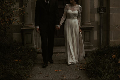 detail of bride and groom holding hands in dramatic, moody lighting