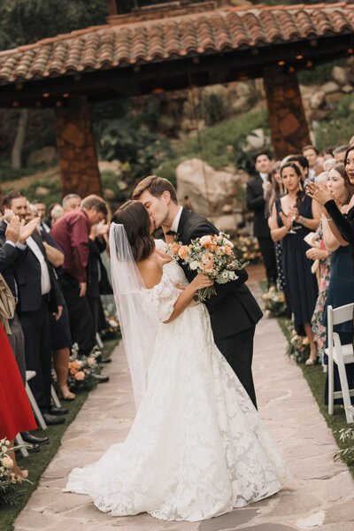 Bride and groom sharing a romantic kiss at the altar at Pala Mesa Resort, surrounded by beautiful scenery
