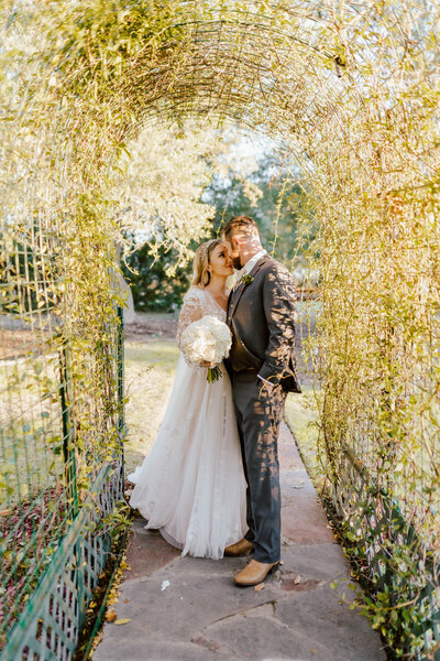 bride and groom standing under botanical arch