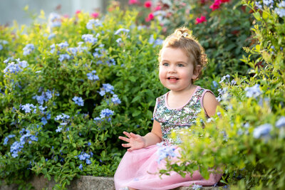 Young girl smiling outside next to flowers