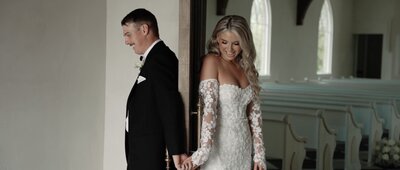 Couple holding hands around the edge of a door during a first touch at a wedding in dallas