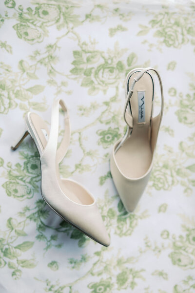 White bridal shoes on green floral background
