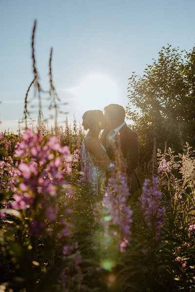 bride and groom kissing surrounded by flowers