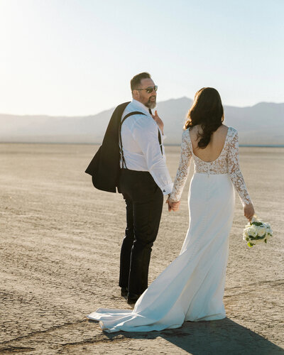 bride and groom walking together after eloping at a dry lake bed in nevada