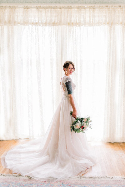 bride stands in front of window in mansion near Omaha