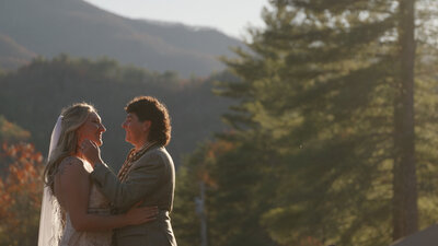 A newlywed couple with their arms around each other while standing in the mountains 