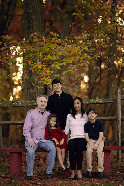 Family of 5 posing for family photos in a NJ park during the fall.