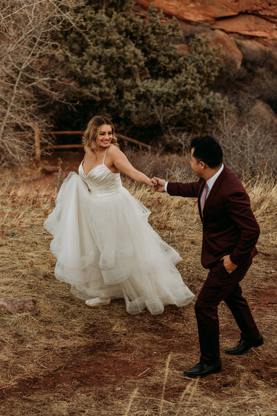 Bride and Groom hold hands and walk along path in Red Rock Park
