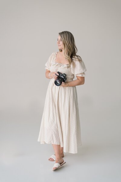 Woman holds camera and poses to capture wedding
