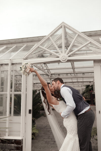 bride and groom kissing in greenhouse