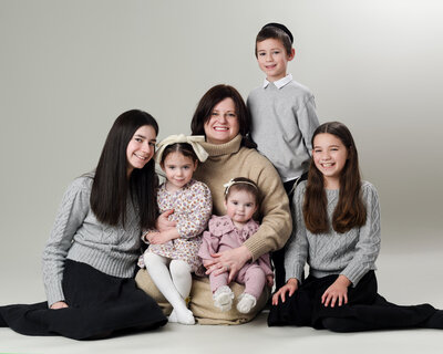 mom sitting on floor with her 5 kids for studio portrait