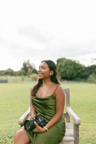 Emily Rohman photographer smiling with green dress holding camera