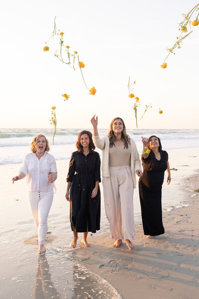 Women in the beach in La Jolla throwing flowers at sunset