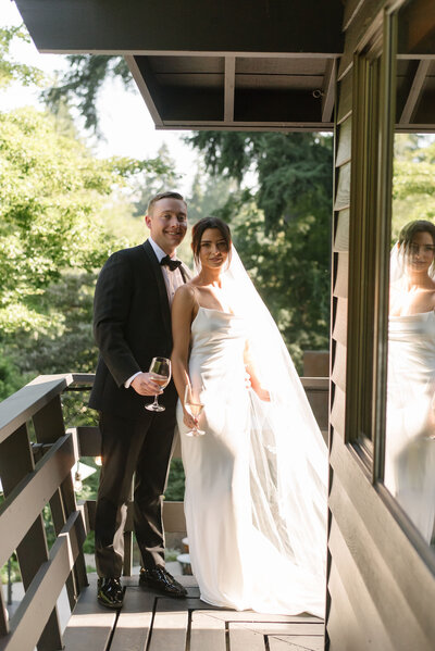 Bride and groom on a wooden balcony at a Pacific Northwest wedding, planned by Seattle wedding planner Wander Event Co., showcasing full-service planning.