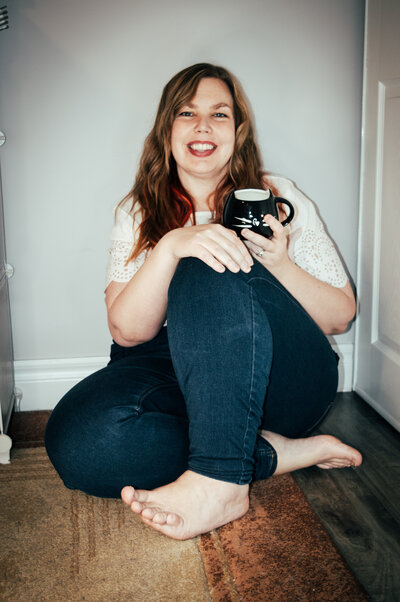 Woman smiling with coffee cup in her hand.
